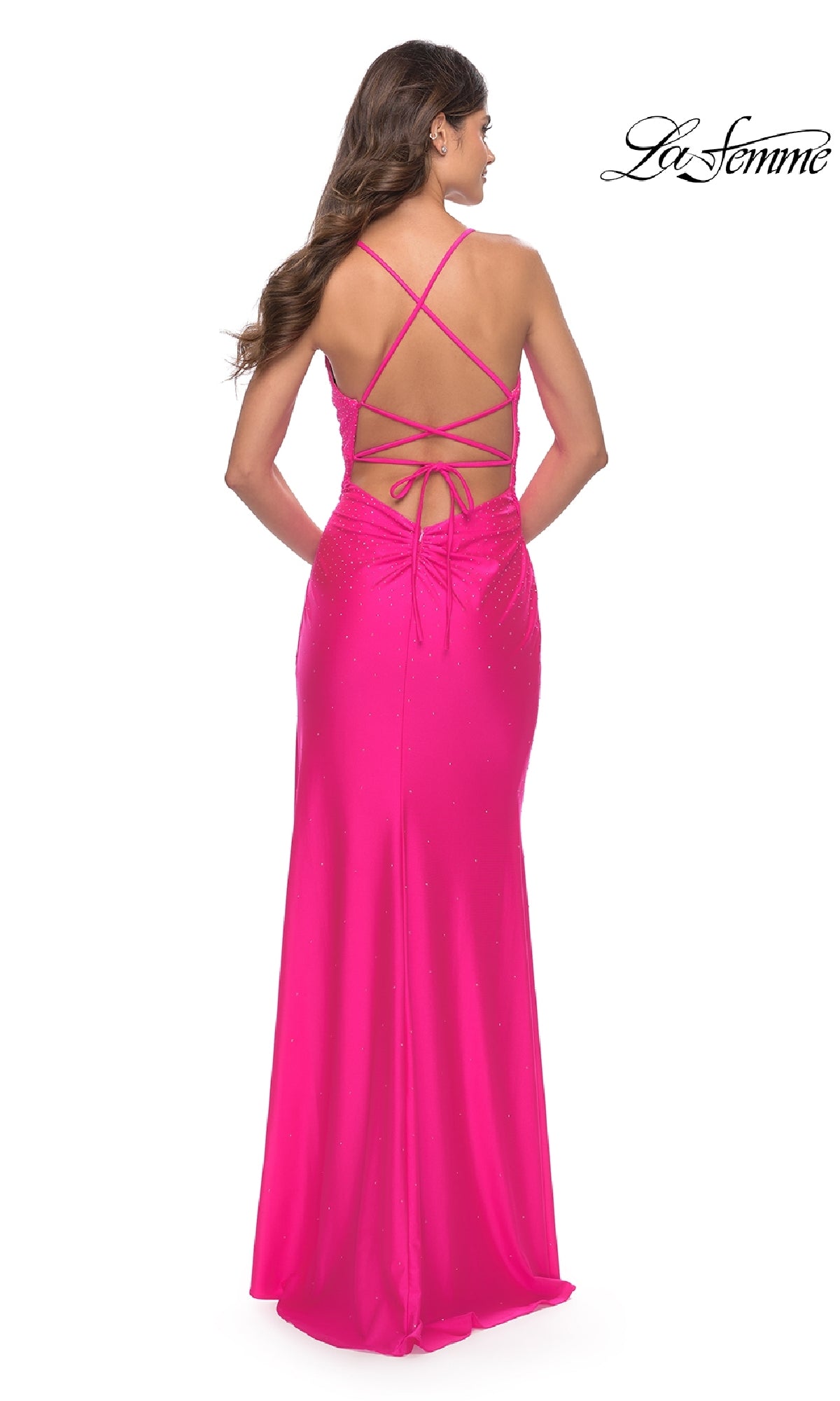 A woman faces away, wearing the La Femme 30683 long neon pink prom dress. The floor-length gown has a fitted silhouette, subtle embellishments, and crisscrossing lace-up open back straps.